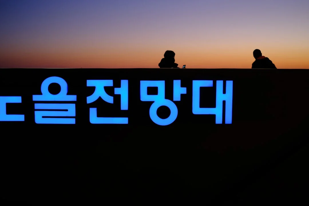 a couple of people sitting on top of a sign