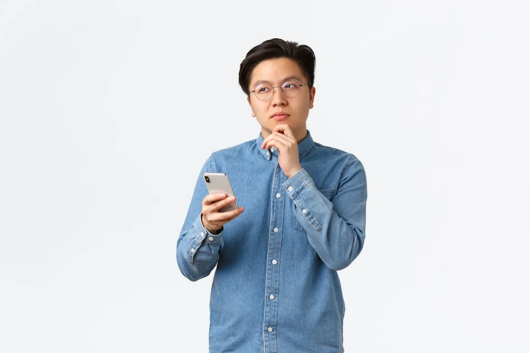 A man in a blue shirt is holding a cell phone