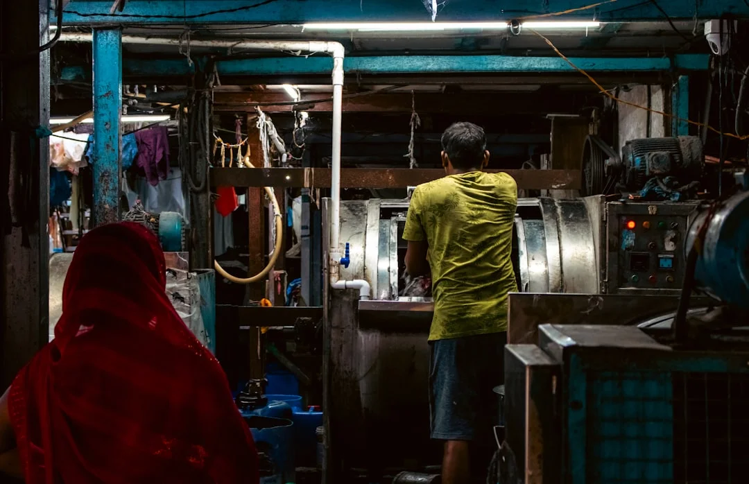 Man working in a dimly lit workshop with laundry machines.