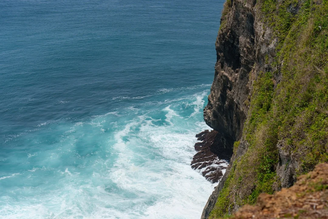 Cliff meets turquoise waves and ocean.