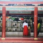 woman in white dress standing on red wooden door