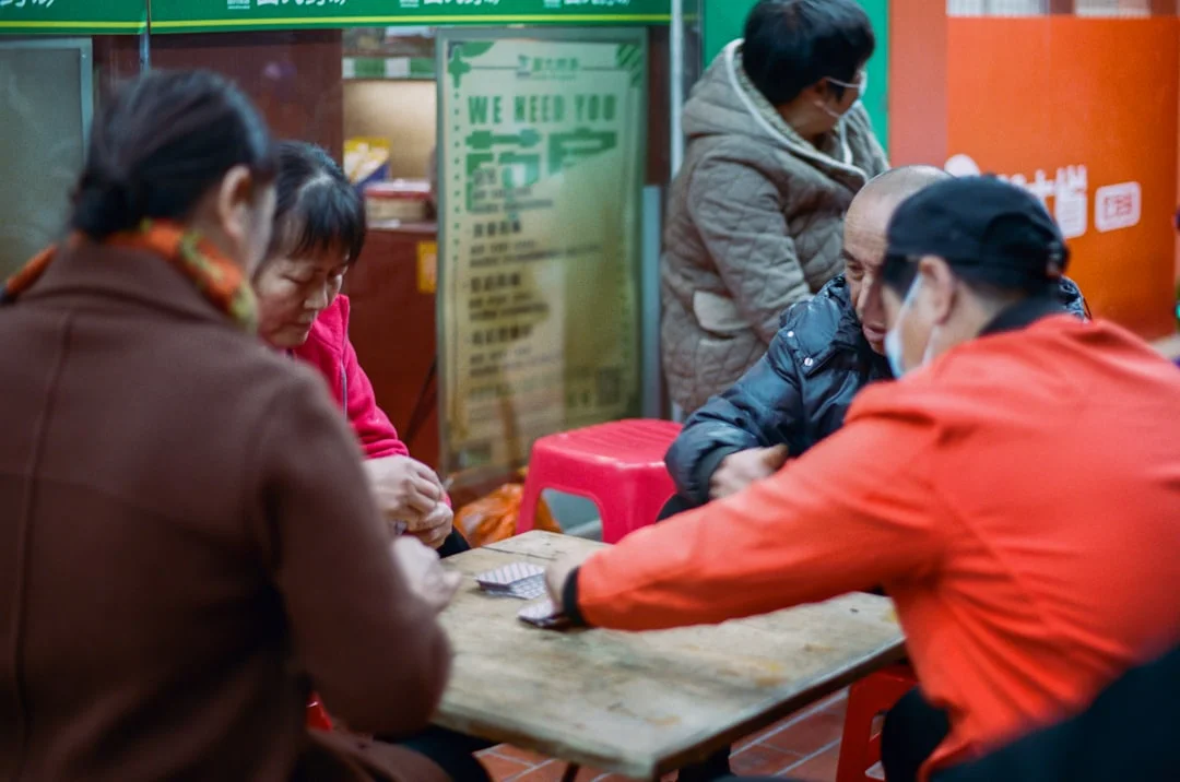 People playing cards around a small table outside.