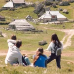 a group of people sitting on top of a lush green hillside