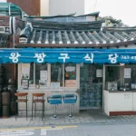 a small asian restaurant with a blue awning