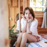 a woman sitting on a bed with her hands on her face