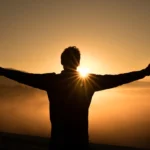 silhouette photo of man on cliff during sunset