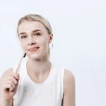 a woman holding a toothbrush in her right hand