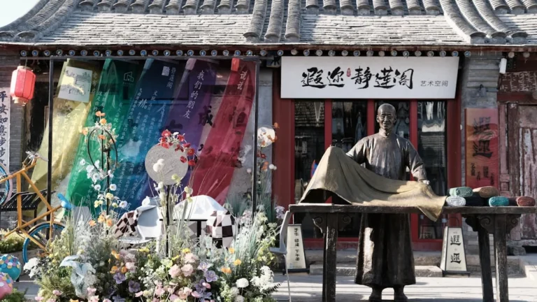 A shop with a statue and colorful fabrics.