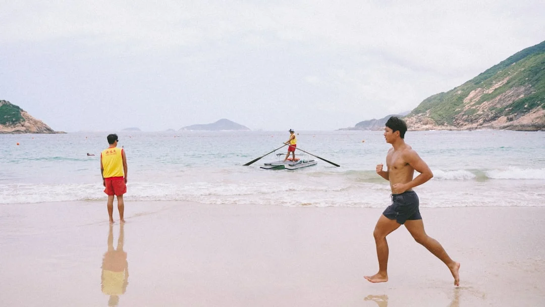 a man running on a beach next to another man