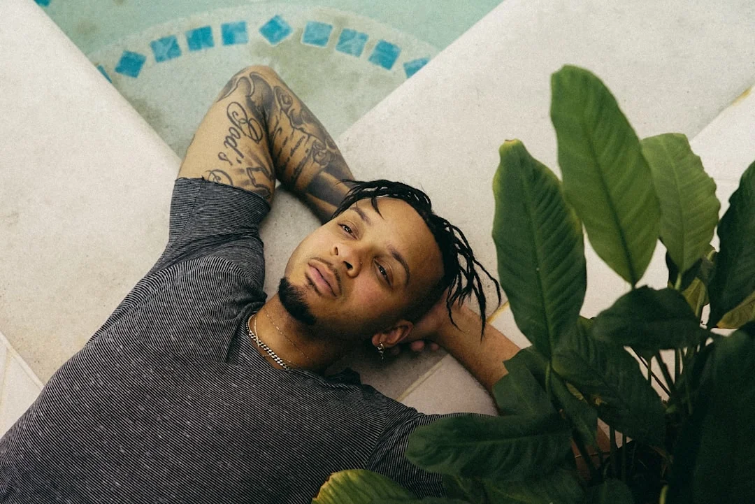 man in gray sweater lying on white and blue floral bed