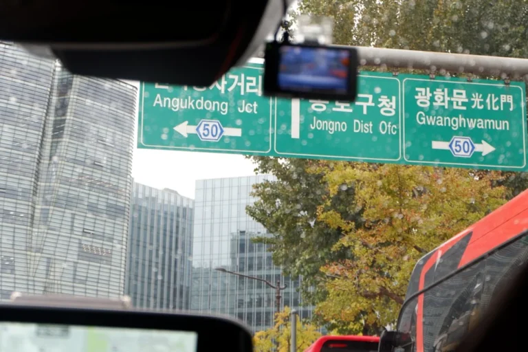 A green street sign hanging from the side of a traffic light