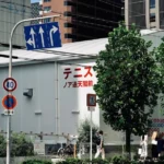 A group of people walking down a street next to tall buildings