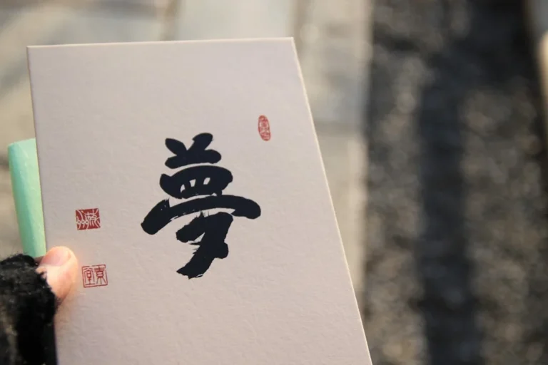 a person holding up a piece of paper with chinese writing on it