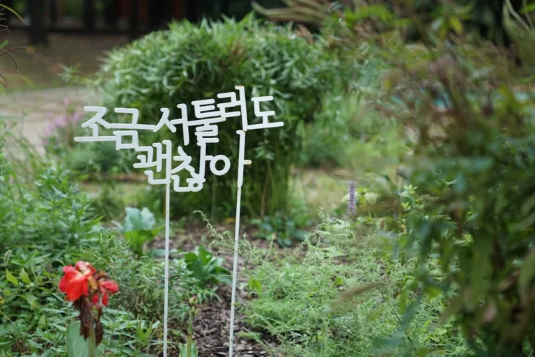 a sign that is in the grass near a flower