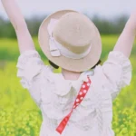 a woman in a hat is standing in a field