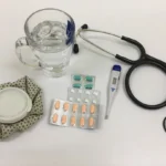 black and silver stethoscope beside clear glass mug