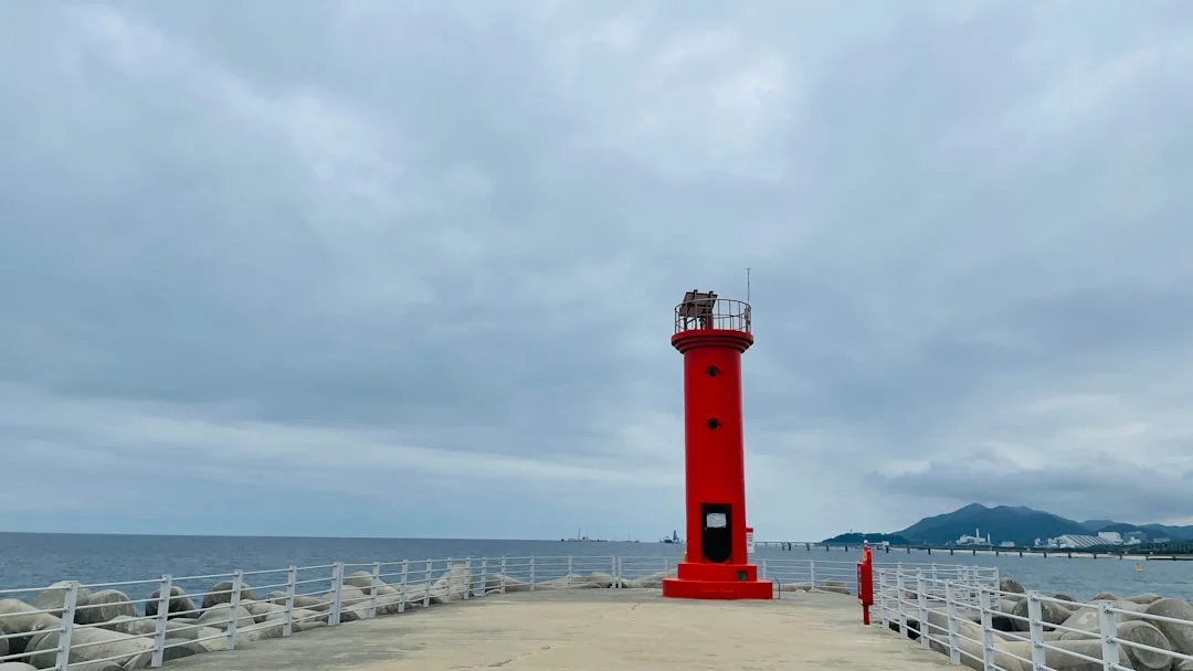 a red light house sitting on top of a pier